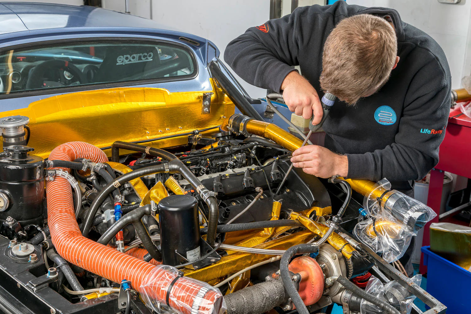 Bourne engineer working on a Noble engine with visible components and tools.