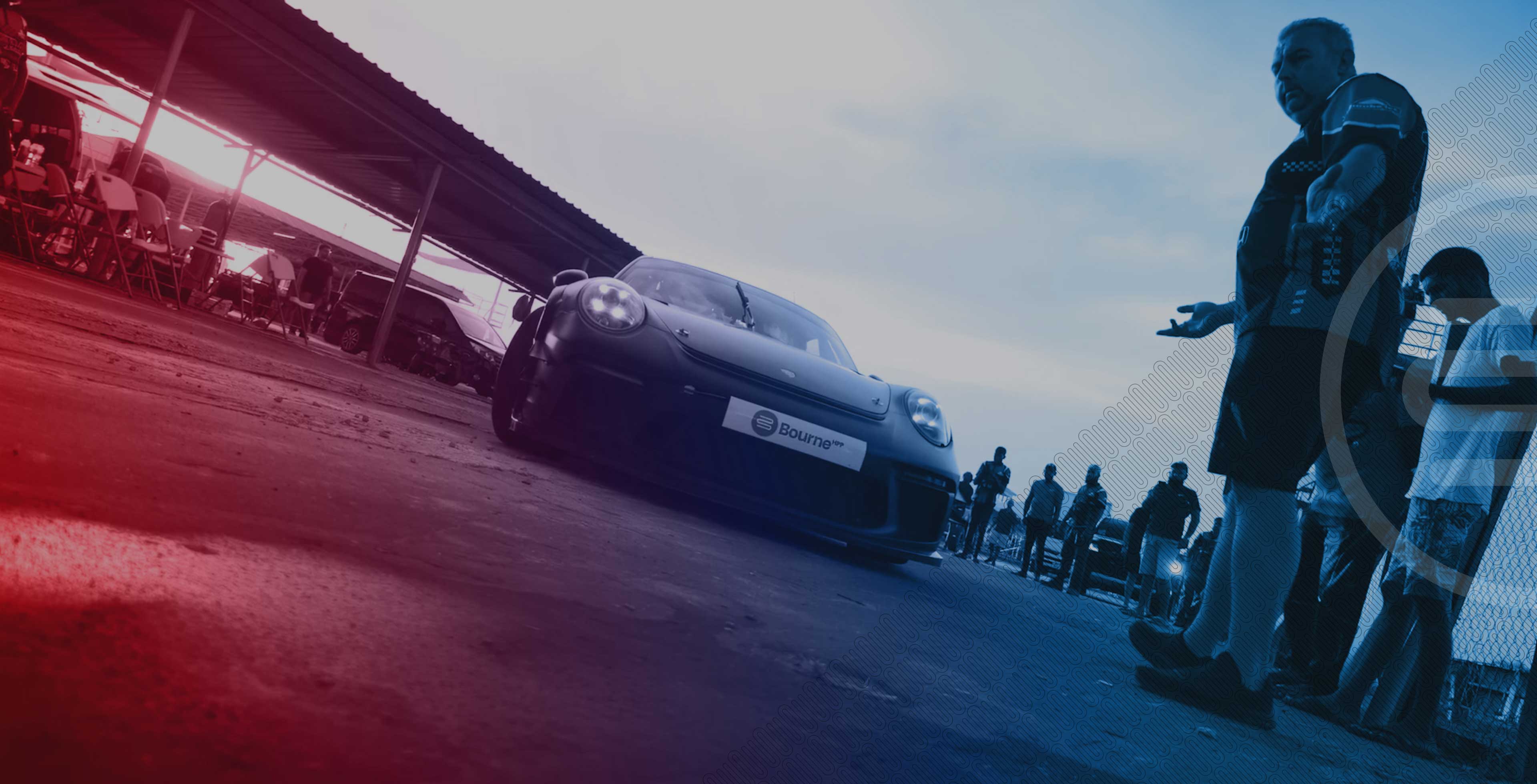 Car eith a Bourne licence plate on a track with people around, likely at a racing event.