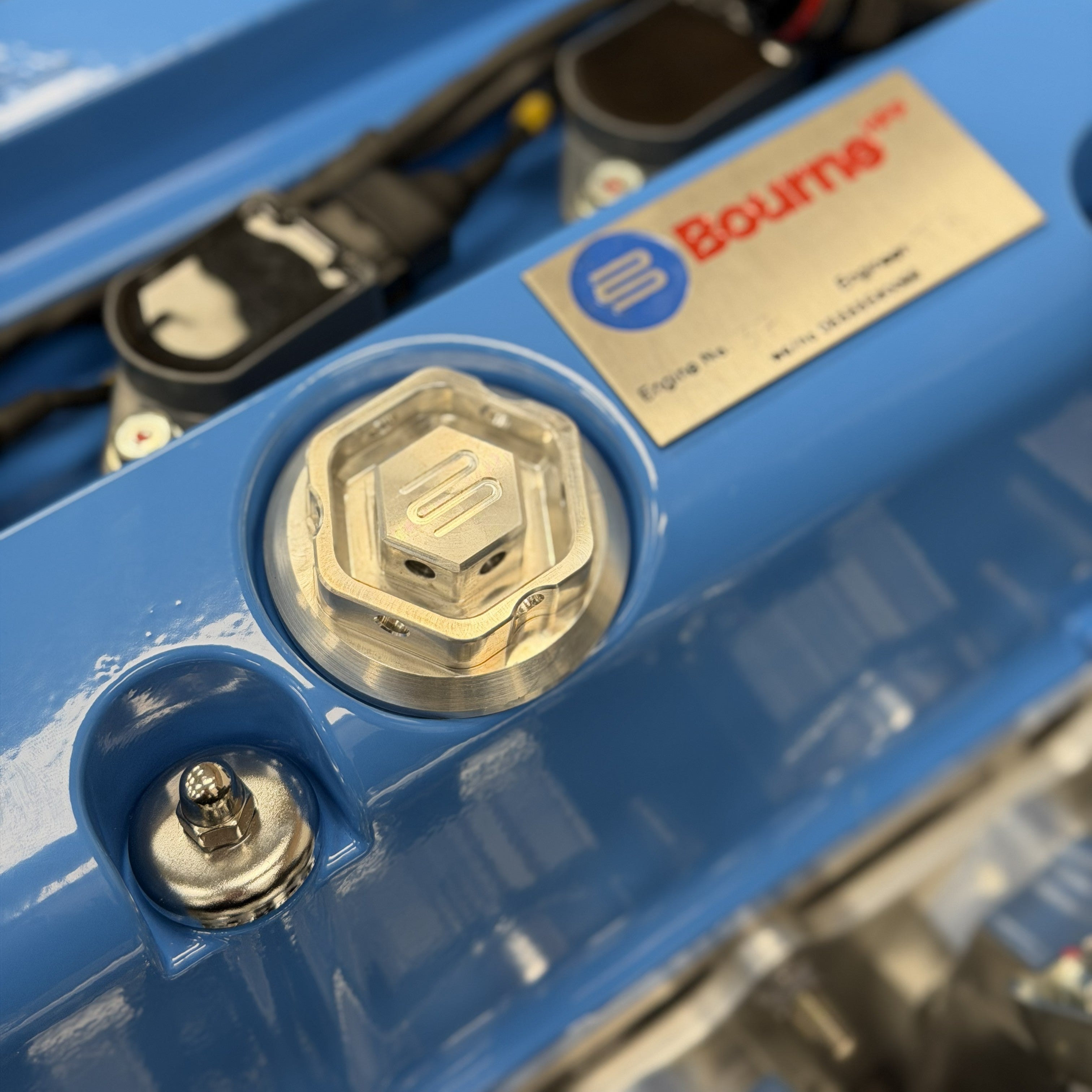 Extreme close up of a Bourne blue Honda engine valve cover with a silver Bourne oil filler cap featured.
