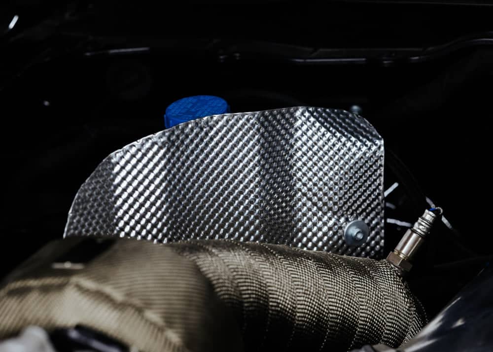 Thick aluminium heat shield for exhaust protection, 0.5mm thick sheet by Funk Motorsport, showing the shiny, durable barrier in a workshop setting.